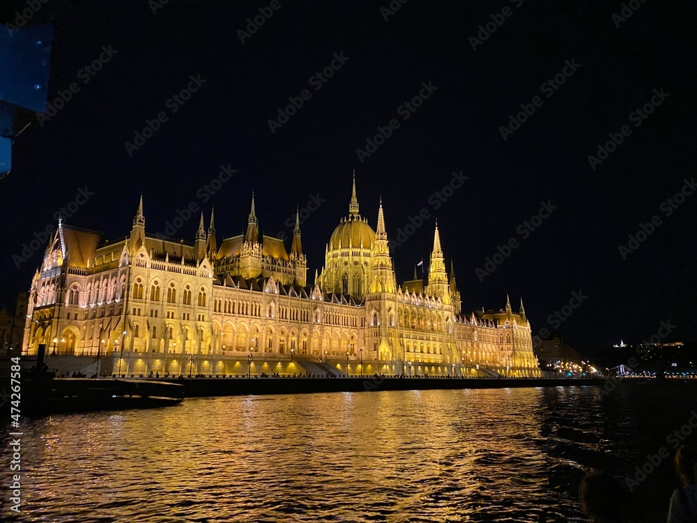 Illuminated Parliament building of Budapest at night with dark sky and reflection in Danube river