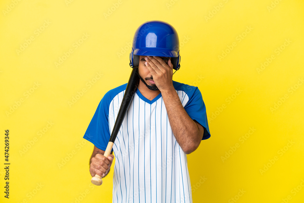 Young Colombian latin man playing baseball isolated on yellow background with tired and sick expression