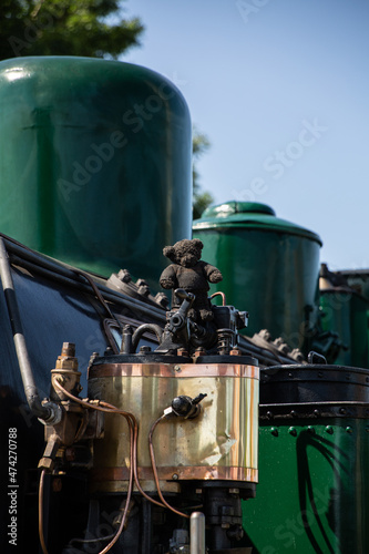 blackened teddy bear on top of copper steam train part