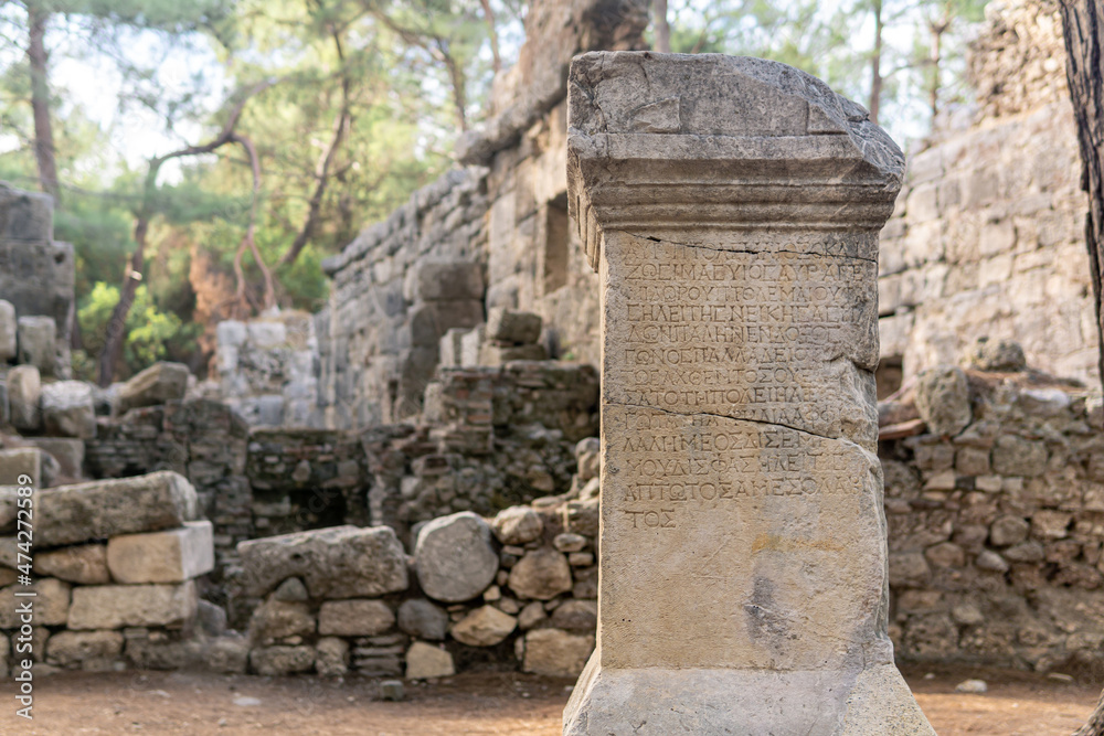 half-erased antique inscription on a stone among the ruins of the ancient city of Phaselis, Turkey