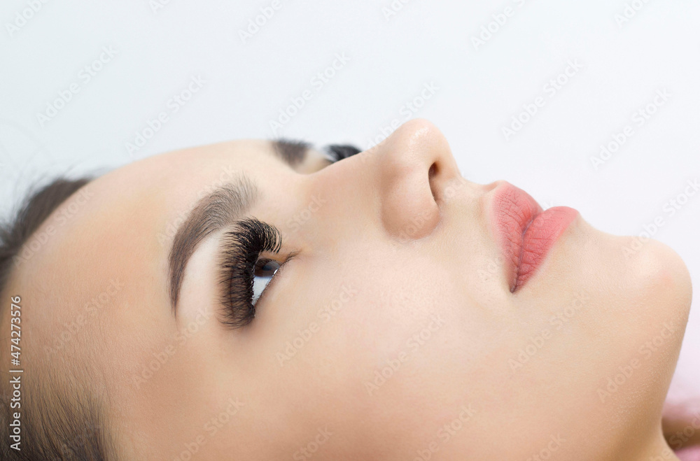 Close-up of the face of beautiful brown female eyes with long eyelashes, smooth healthy skin. Eyelash extension procedure. Good eyesight, contact lenses. Health and eye care.