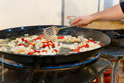 Cooking process of a traditional Valencian paella in a paella pan, with a gas fire.