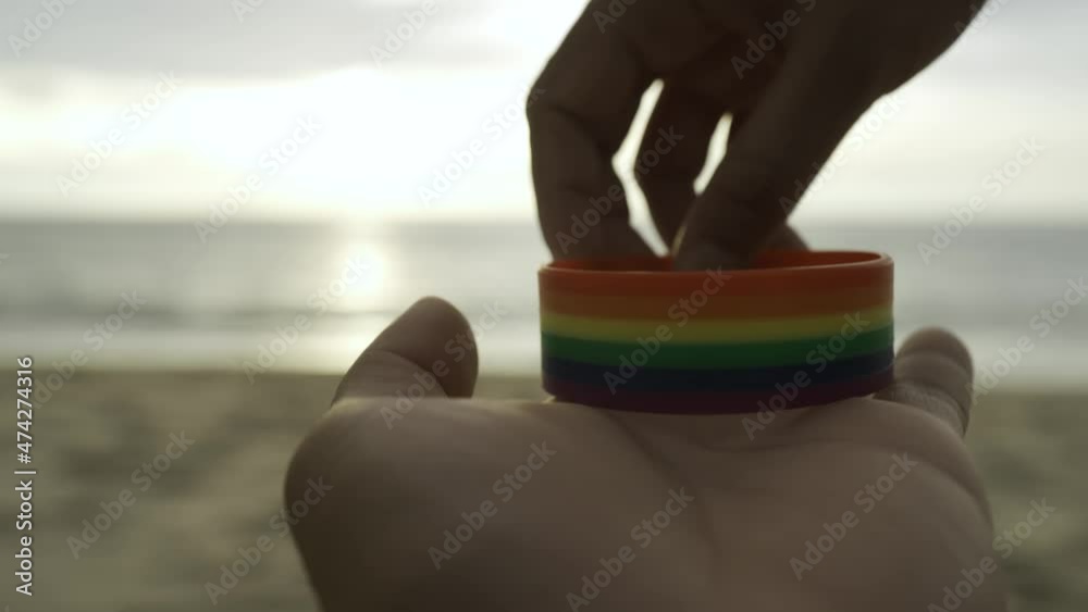 ็Hand in a rainbow bracelet. Gay pride month event day.Colorful rainbow symbol flag.Pattern LGBTQ+ concept. Close up. ็Hand in a rainbow bracelet. Gay pride month event day.Colorful rainbow symbol flag.Pattern LGBTQ+ concept. Close up.
