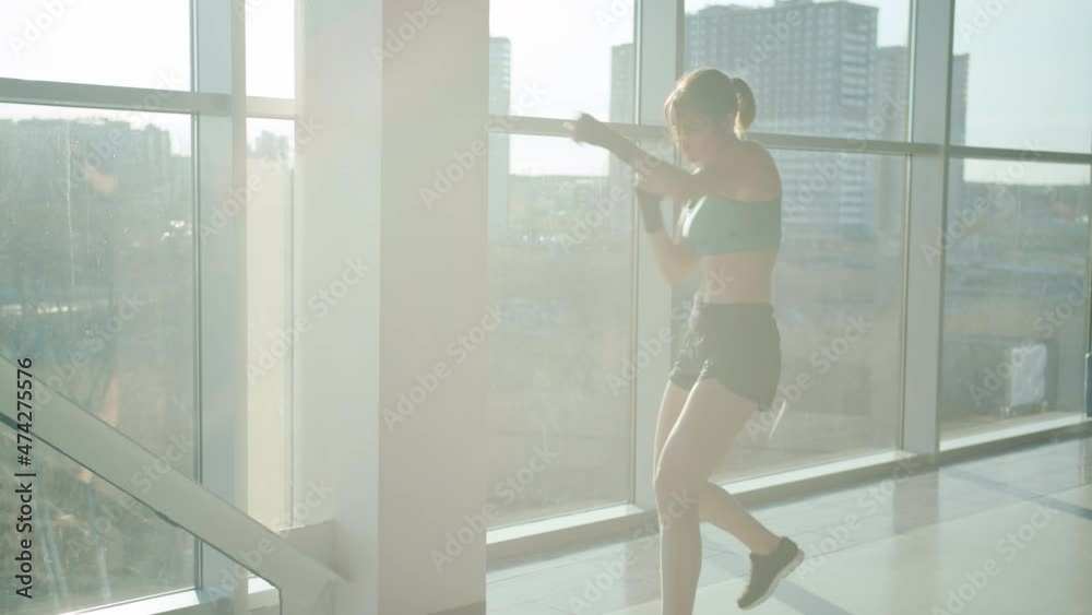 Attractive young girl is boxing in urban gym with glass walls concentrated on training alone. Fitness and healthy lifestyle concept. Attractive young girl is boxing in urban gym with glass walls concentrated on training alone. Fitness and healthy lifestyle concept.