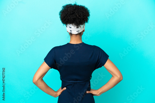 Young latin woman isolated on blue background in back position