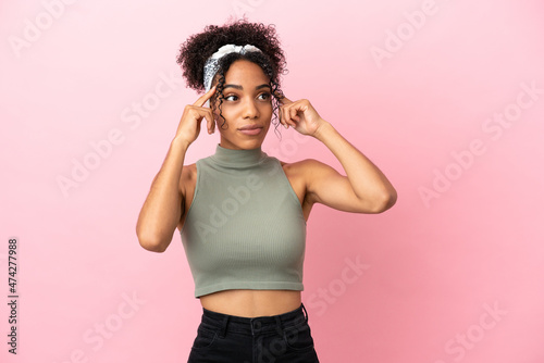 Young latin woman isolated on pink background having doubts and thinking