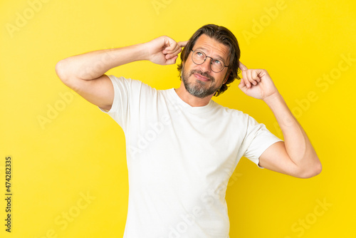 Senior dutch man isolated on yellow background having doubts and thinking © luismolinero