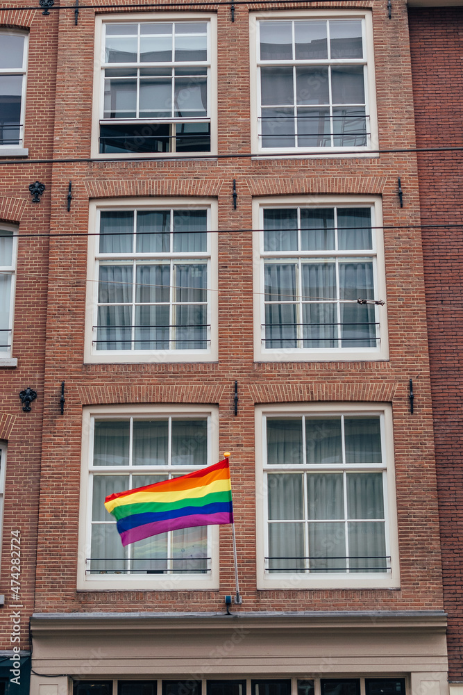 Gay flag in Amsterdam. Gay rainbow flag on a building. Rainbow flag of the LGBT community on the building on street Amsterdam. 
