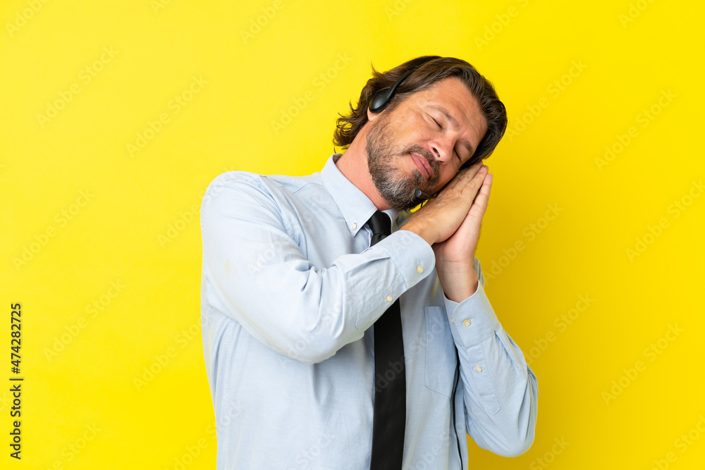 Telemarketer dutch man working with a headset isolated on yellow background making sleep gesture in dorable expression Telemarketer dutch man working with a headset isolated on yellow background making sleep gesture in dorable expression