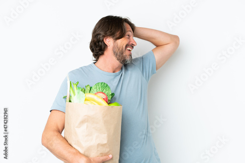 Senior dutch man holding grocery shopping bag over isolated background smiling a lot