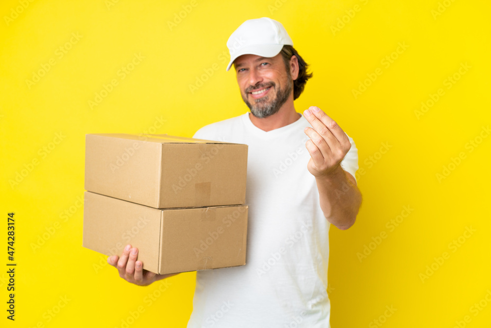 Delivery senior dutch man isolated on yellow background making money gesture Delivery senior dutch man isolated on yellow background making money gesture