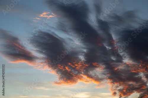 Typical sky with dense exotic clouds colored in orange, gray and white against a background of blue sky