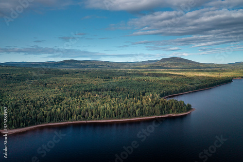 Green forest and lakeshore at Lake Siljan from above with blue sky in Dalarna, clouds in sky, Sweden. photo