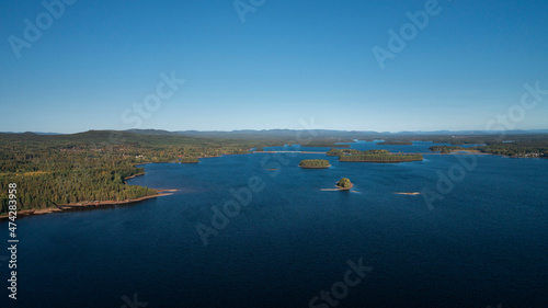Green forest and lakeshore with islands at Lake Siljan from above with blue sky in Dalarna, clouds in sky, Sweden. photo