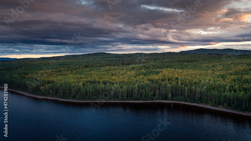 Green forest and lakeshore at Lake Siljan from above during sunset in Dalarna, Sweden. photo