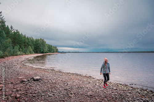 Woman walking at beach and lakeshore with forest at Lake Siljan in Dalarna, Sweden. photo