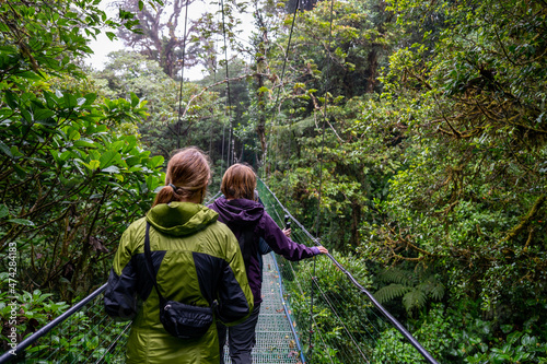Woman and teenage girl crossing a suspension bridge in the Cloud Forest of Costa RIca.