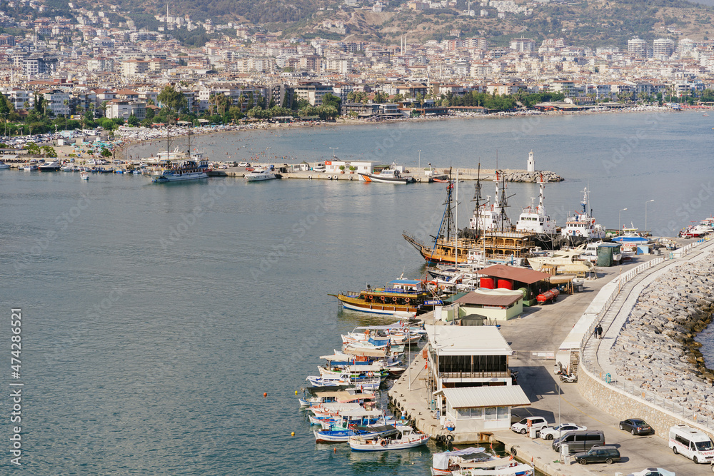 Alanya, Turkey - 24 July 2021: Sea pier port for yachts and boats in marina on a background of mountainous terrain. Sea coast
