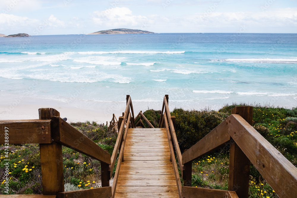 Relaxing summer-day beach background following the wooden path, in Western Australia. Calmness and motivational background design.