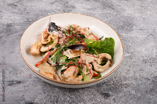 seafood salad. on a white plate on a gray table background
