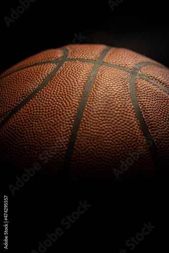 Detail of orange basketball ball with black background.