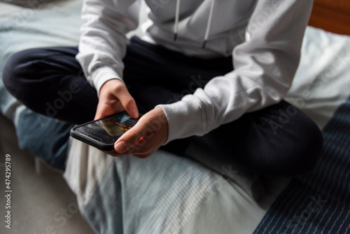 Fotografija Close up of hands of teen boy in white sweater texting on phone.