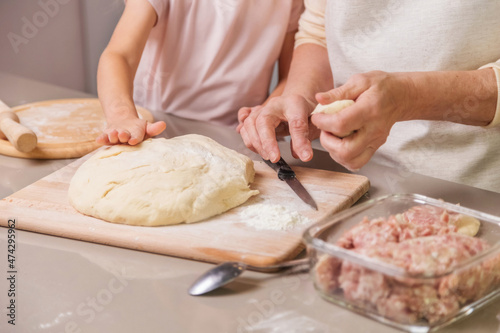 grandmother and girl preparing a meat dish