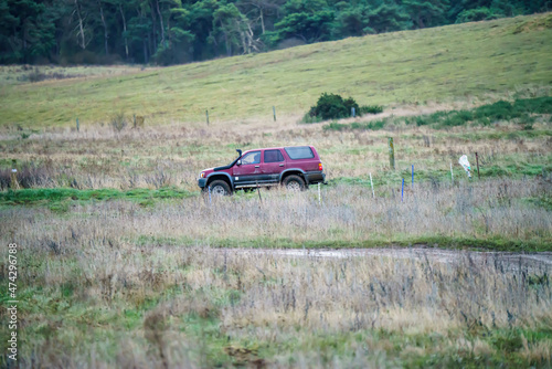Toyota Hilux Surf 4Runner 4x4 off-road vehicle driving across mud, water-logged terrain and wading through deep water pools, Wilts UK. 