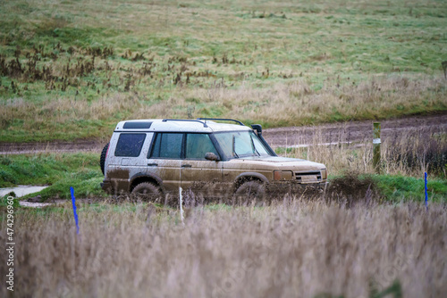 Land Rover Discovery 4x4 off-road vehicle driving across mud, water-logged terrain and wading through deep water pools, Wilts UK.  © Martin