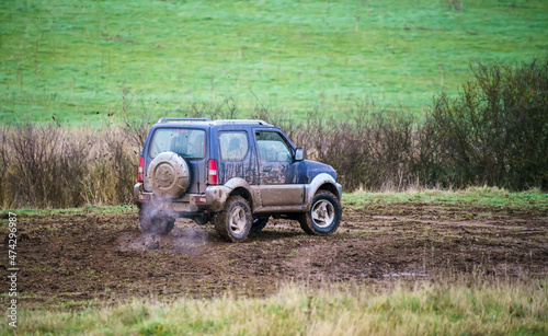 4x4 off-road vehicle driving across mud and water-logged terrain, Wilts UK. Suzuki Jimny © Martin