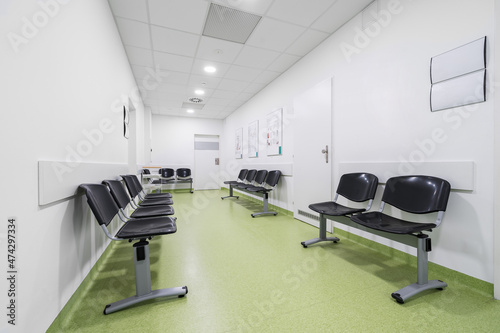 Chairs lined up in a hospital waiting room. Hospital interior with green floor without people.