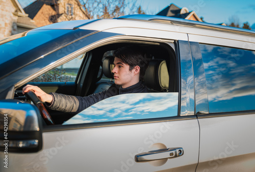 Teenage boy sitting in driver's seat of vehicle learning to drive.