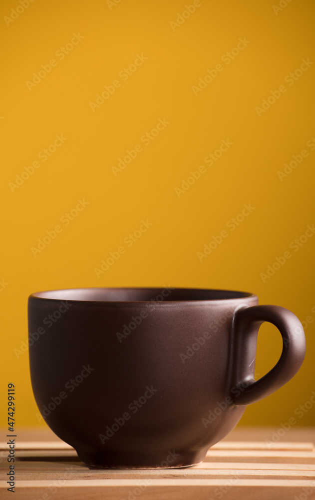 brown cup with coffee or chocolate on wood, with yellow background brown cup with coffee or chocolate on wood, with yellow background