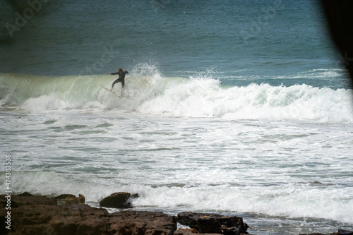 male surfer catching waves surfing at south coast beach on a bright warm sunny day on clear blue water
