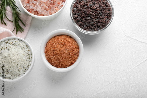 Different kinds of salt on white table, flat lay. Space for text