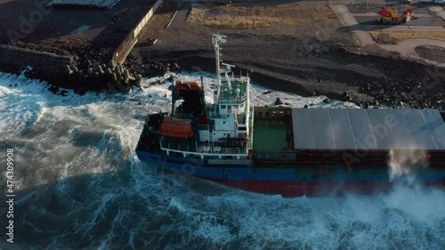 A large seagoing vessel dry cargo ship washed ashore during a strong storm wind and ran aground. The dry cargo ship washed ashore during a sea storm. Oil spills. A sea-going cargo ship washed ashore 