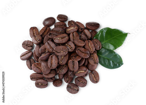 Pile of roasted coffee beans with fresh leaves on white background, top view