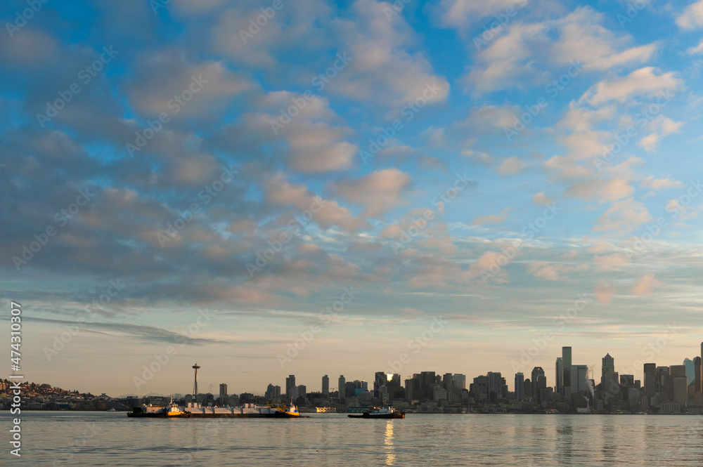Seattle Skyline at Dawn. Sunrise on Elliott Bay when marine traffic is active with ferries and tugboats crisscrossing the water with the beautiful city skyline in the background.