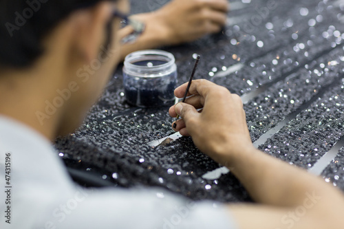 Handicraft tailor embroidering black sequins beads onto tulle. Making a dress.