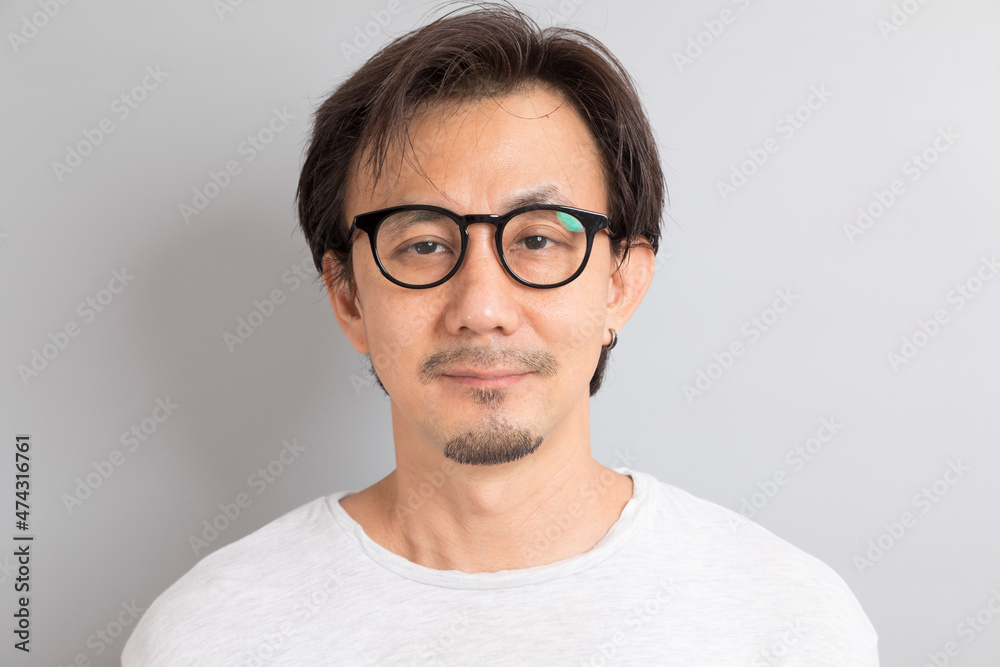 Close up portrait of Asian man wearing eyeglasses on grey background.