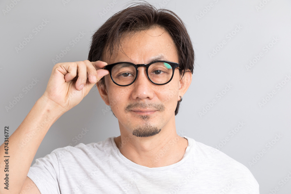 Close up portrait of Asian man wearing eyeglasses on grey background.