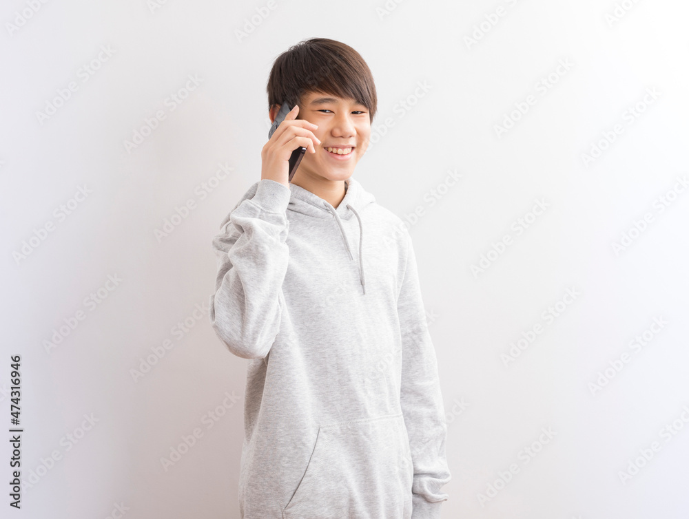 Asian teen boy schooler texting or playing game online on smartphone isolate on white background. Asian teen boy schooler texting or playing game online on smartphone isolate on white background.
