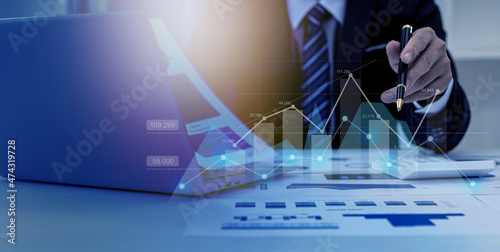 A business man examines data on financial documents, company financial reports, graphics showing financial and numerical growth data. The concept of financial management to grow and be profitable. photo