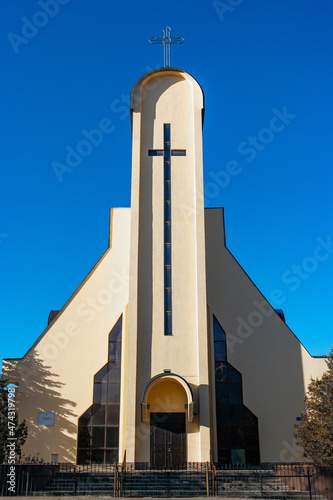 Catholic white tower church with big cross on a deep blue sky photo