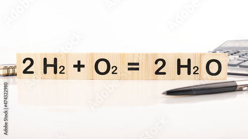 Reaction of Hydrogen and Oxygen to water inscription on wooden cubes on a white background 2H2 plus O2 equals 2H2O
