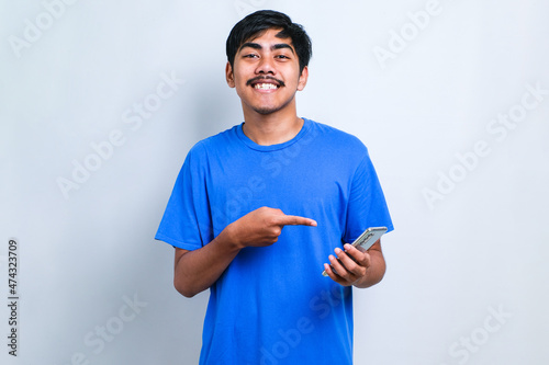 Man using smartphone wearing casual shirt iery happy pointing with hand and finger photo