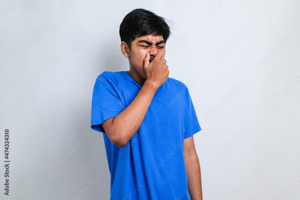 Asian man smelling something stinky and disgusting, intolerable smell, holding breath with fingers on nose. Bad smell Asian man smelling something stinky and disgusting, intolerable smell, holding breath with fingers on nose. Bad smell