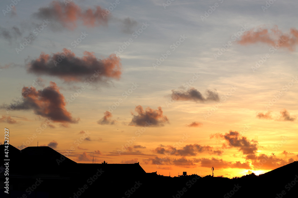 clouds at sunset over the silhouettes of residential houses