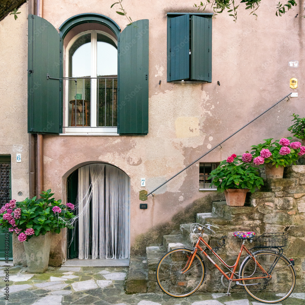Mediterranean house with flowers, outside stairs, and vintage bicycle