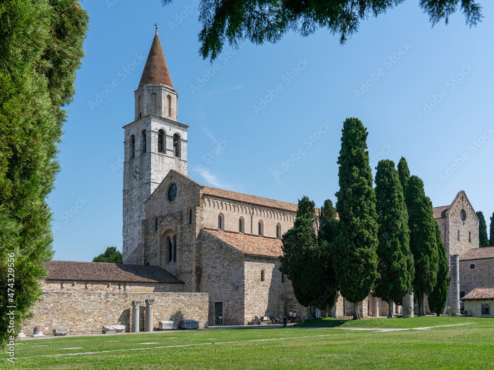 Basilica of Aquileia with cypress trees, and lawn in the foreground